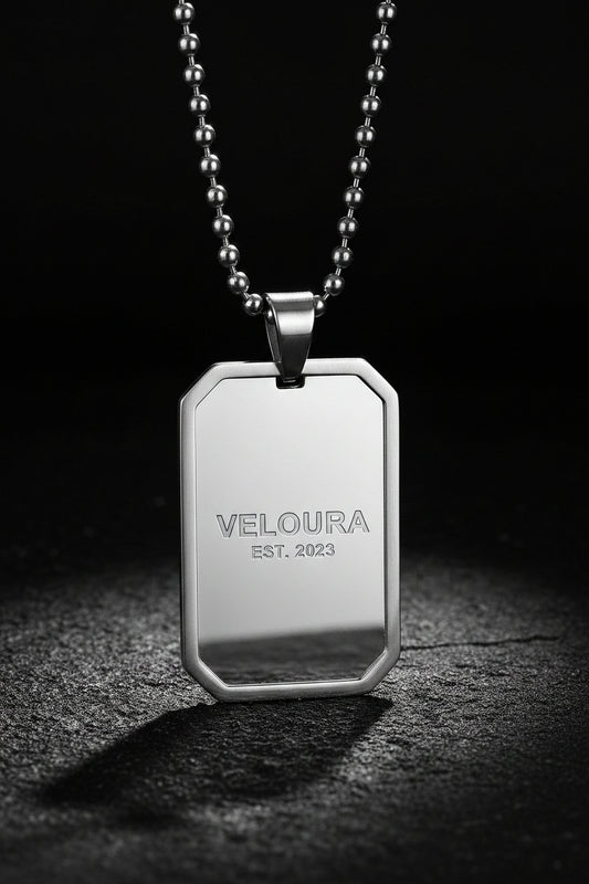 Stainless steel dog tag pendant on a chain against a white background
